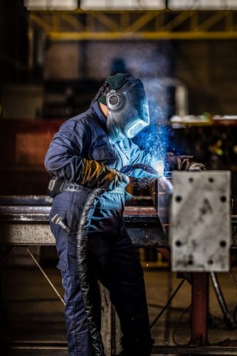 Lasser aan het werk op bouwplaats vastgelegd in industriële fotografie